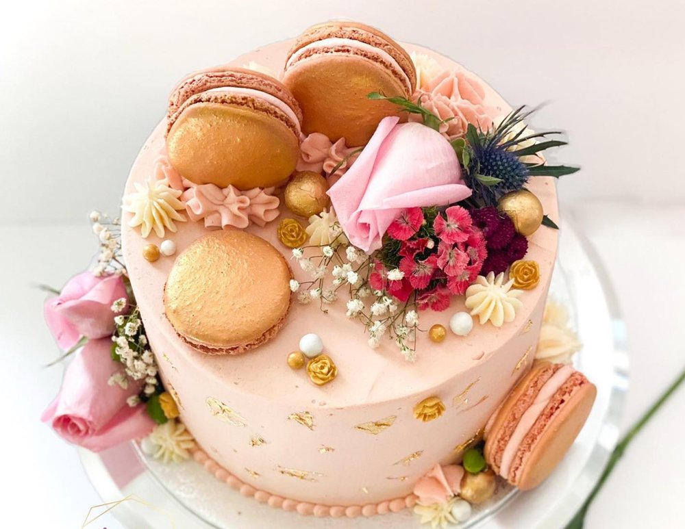 A Sprinkles by Ameera cake finished with gold-leaf macarons, fresh roses, and dried florals